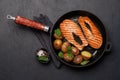 Grilled salmon steaks and potatoes sizzling in a frying pan