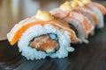 Grilled salmon sushi roll, japanese food style on black ceramic Royalty Free Stock Photo