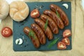 Grilled sausage with the addition of herbs and vegetables on the grill plate, outdoors. Royalty Free Stock Photo