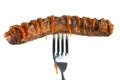 Grilled sausage decorated with ketchup pierced on a fork, isolated on white Royalty Free Stock Photo
