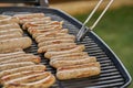 Grilled Sausage on the flaming Grill. BBQ. Bearbeque outdoors. Large quantity of sausages on the barbecue and with the pincer Royalty Free Stock Photo