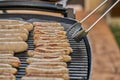 Grilled Sausage on the flaming Grill. BBQ. Bearbeque outdoors. Large quantity of sausages on the barbecue and with the pincer Royalty Free Stock Photo