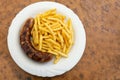 Grilled sausage, German Bratwurst, and french fries on a plate in a fast food restaurant, tasty but unhealthy eating with trans