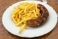 Grilled sausage, German Bratwurst, and french fries on a plate in a fast food restaurant, tasty but unhealthy eating with trans