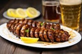 grilled sausage links on a plate next to a filled lager glass Royalty Free Stock Photo