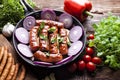 Grilled sausage with onion in a pan, raw meat and vegetables Royalty Free Stock Photo