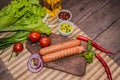 Grilled sausage with pasta, slices of bread, herbs and cherry tomatoes. Top view. On a wooden rustic brown background Royalty Free Stock Photo