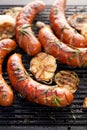 Grilled sausages with the addition of herbs and vegetables on the grill plate, outdoor, close-up Royalty Free Stock Photo