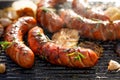 Grilled sausages with the addition of herbs and vegetables on the grill plate, outdoors, close-up. Royalty Free Stock Photo