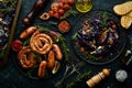 Grilled sausages, and baked red cabbage with cheese, rosemary and cranberries on a black plate. Traditional German dish. Royalty Free Stock Photo