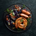 Grilled sausages, and baked red cabbage with cheese, rosemary and cranberries on a black plate. Traditional German dish. Royalty Free Stock Photo