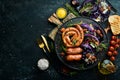 Grilled sausages, and baked red cabbage with cheese, rosemary and cranberries on a black plate. Traditional German dish. Royalty Free Stock Photo