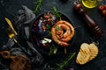 Grilled sausages, and baked red cabbage with cheese, rosemary and cranberries on a black plate. Traditional German dish. Royalty Free Stock Photo