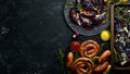 Grilled sausages, and baked red cabbage with cheese, rosemary and cranberries on a black plate. Traditional German dish. Royalty Free Stock Photo