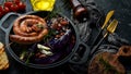 Grilled sausages, and baked red cabbage with cheese, rosemary and cranberries on a black plate. Traditional German dish. Royalty Free Stock Photo