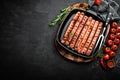 Grilled sausages bratwurst in grill frying-pan on black background. Top view. Traditional German cuisine