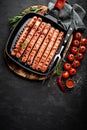 Grilled sausages bratwurst in grill frying-pan on black background. Top view. Traditional German cuisine Royalty Free Stock Photo