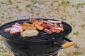 grilled sausages, cevapcici and meat on black bbq grill in the sand, grill barbecue on summer beach Royalty Free Stock Photo