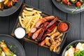 grilled sausages french fries ketchup and mayonnaise sauce on cutting board on wooden background, top view Royalty Free Stock Photo