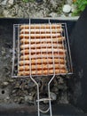 Grilled sausages on grill with smoke and flame on dark background Royalty Free Stock Photo