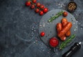 Grilled sausages with herbs, incisions, on slate stone plate round, dark background Royalty Free Stock Photo