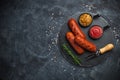 Grilled sausages with herbs, incisions, on slate stone plate round, dark background Royalty Free Stock Photo