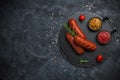 Grilled sausages with herbs, incisions, on slate stone plate round, dark background Royalty Free Stock Photo