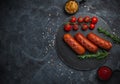 Grilled sausages with herbs, incisions, on slate stone plate round, dark background Royalty Free Stock Photo