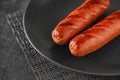 Grilled sausages with incisions, on gray plate dark background, selective focus Royalty Free Stock Photo