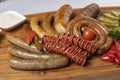 Grilled sausages platter with pickled cherry tomatoes, sauce Royalty Free Stock Photo