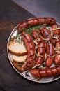 Grilled sausages with onion served with bread on a plate, on a wood background, top view. Roasted, fried meat sausages. Royalty Free Stock Photo