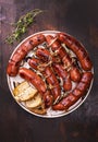 Grilled sausages with onion served with bread on a plate, on a wood background, top view. Roasted, fried meat sausages. Royalty Free Stock Photo