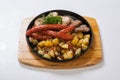 Grilled sausages with potatoes, and roasted meat on a grill pan Royalty Free Stock Photo