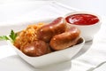 grilled sausages, potatoes and sauerkraut on cooking pan, on white background Royalty Free Stock Photo