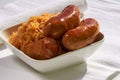 Grilled sausages, potatoes and sauerkraut in a white plate Royalty Free Stock Photo