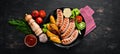 Grilled sausages with potatoes and vegetables on a black stone background. Meat. Royalty Free Stock Photo