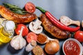 Grilled sausages, vegetables, hot peppers and various spices and ingredients on a black background Royalty Free Stock Photo