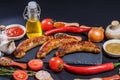 Grilled sausages, vegetables, hot peppers and various spices and ingredients on a black background Royalty Free Stock Photo