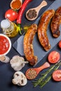 Grilled sausages, vegetables, hot peppers and various spices and ingredients on a black background Royalty Free Stock Photo