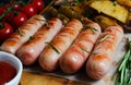 Grilled sausages on a wooden chopping Board. Fried potatoes, rosemary, tomatoes, tomato ketchup. Unhealthy diet Royalty Free Stock Photo