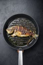 Grilled sea bream or dorado raw fish on grill hot pan over textured black background,  top view Royalty Free Stock Photo