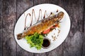 Grilled sea fish with greens and lemon on wooden background. Top view.