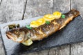 Grilled sea fish with lemon on stone slate background close up. Healthy food. Royalty Free Stock Photo