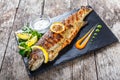 Grilled sea fish with lemon on stone slate background close up. Healthy food. Royalty Free Stock Photo