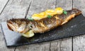 Grilled sea fish with lemon on stone slate background close up. Healthy food. Top view. Royalty Free Stock Photo
