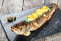 Grilled sea fish with lemon on stone slate background close up. Healthy food. Top view. Royalty Free Stock Photo