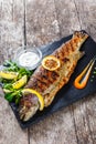 Grilled sea fish with lemon on stone slate background close upGrilled sea fish with lemon on stone slate background close up