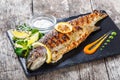 Grilled sea fish with lemon on stone slate background close up. Healthy food. Top view.