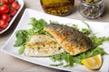 Grilled seabass fillet with arugula, lemon, tomatoes and capers.