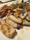 Grilled seafood platter with squid, shrimp, and herbs on a white plate Royalty Free Stock Photo